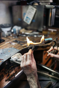 Cropped hands of person using flame torch at workshop