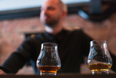 Close-up of scotch whiskey in glasses with man in background at bar