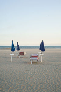 Chairs on beach against clear sky