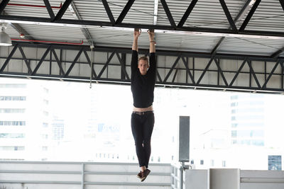 Full length portrait of young woman standing against ceiling