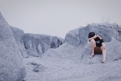 Full length of shirtless woman lying on rock