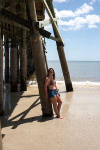 Woman standing against pier at beach
