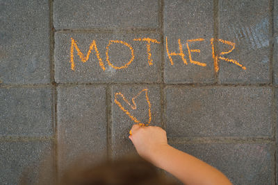 Cute boy draws the word mother with chalk. the boy loves his mother.