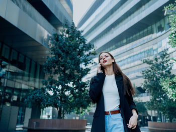 Portrait of young woman standing in city