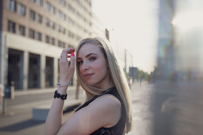 Portrait of smiling young woman standing on street in city