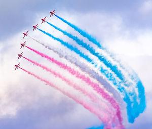 Low angle view of fighter plane performing smoking stunt against cloudy sky