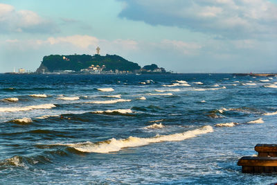 Scenic view of sea with crashing waves against sky