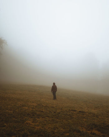 Man on field against sky during foggy weather