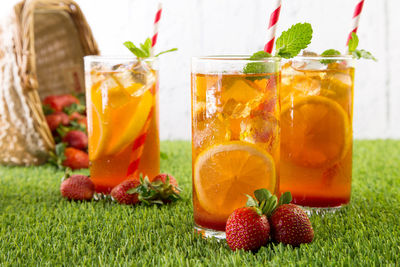 Close-up of strawberry lemon drink in glass on grassy field