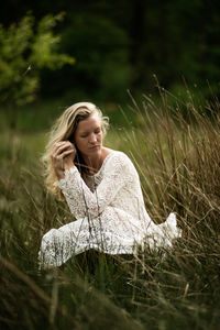 Woman in white dress crouching on field