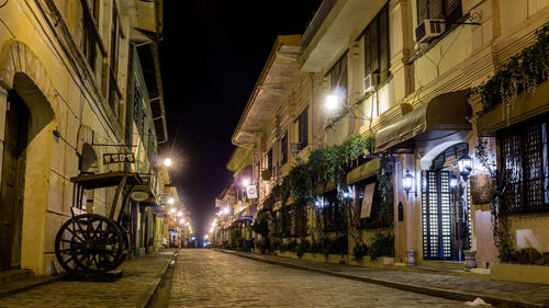 Illuminated street amidst buildings at night