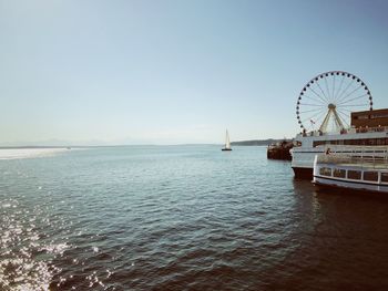 Ferris wheel by sea against clear sky