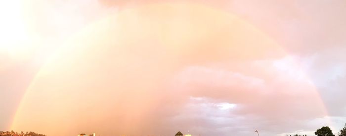 Low angle view of sunlight streaming through clouds during sunset