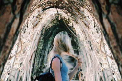 Female hiker standing on walkway amidst plants at forest