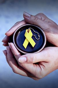 Cropped hands holding yellow ribbon on container