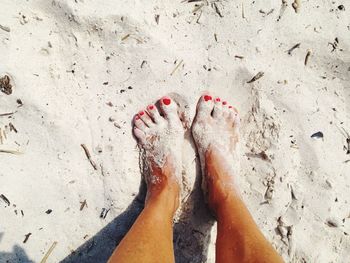 Low section of woman on sand during sunny day