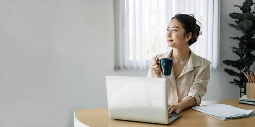 Mid adult woman drinking coffee cup on table