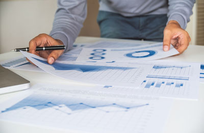 Midsection of man holding paper with text on table