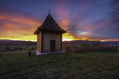 Building on field against sky during sunset