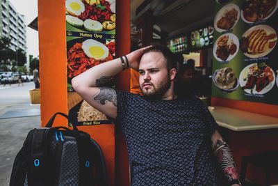 Man looking away while sitting at sidewalk cafe