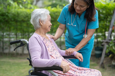 Doctor caregiver help and care asian senior woman patient sitting on wheelchair  