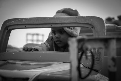 Boy in car against sky