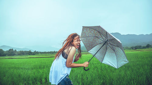 Woman with umbrella standing on field