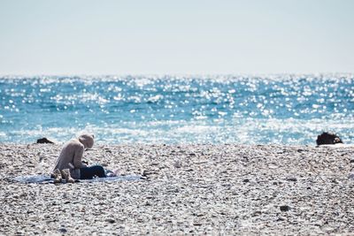 Side view of woman sitting at beach