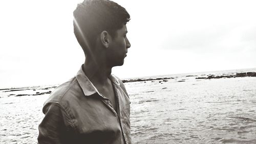 Young man standing on beach against sky