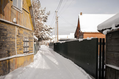 Snow covered street amidst buildings against sky