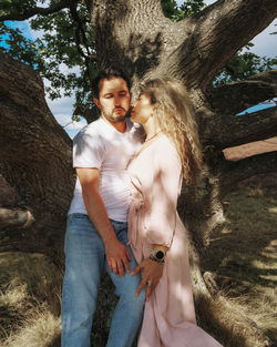 Portrait of couple standing under shadow of tree in park