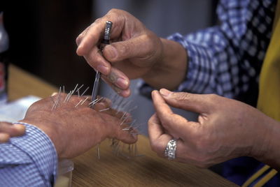 Midsection of man piercing nails on human hand