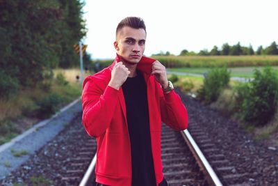 Portrait of young man standing on railroad track