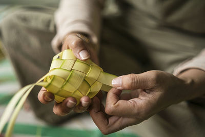 Weaving the coconut leaves making the ketupat, a traditional malay cuisine for eid celebration.