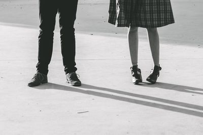 Low section of man and woman standing on footpath