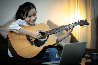 Cute girl playing guitar at home