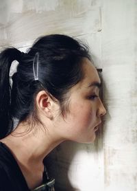 Close-up of young woman standing by wall