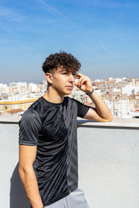 Full length of young man drinking glass against cityscape