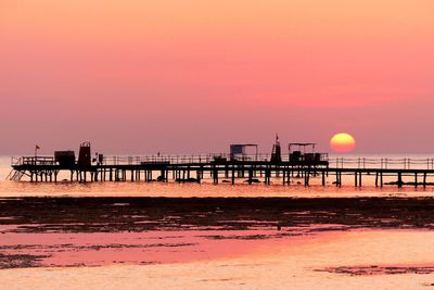 Pier over sea against sky during sunset