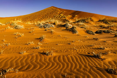 Sand dune in desert against clear sky