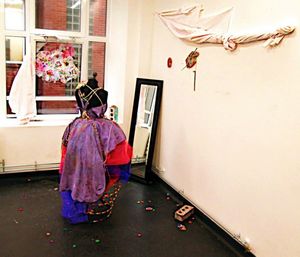 Rear view of woman standing against wall at home