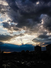 Silhouette buildings in city against sky at sunset