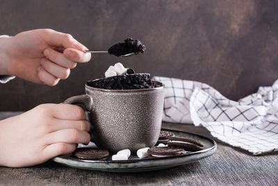 Children's hands take chocolate cake from a mug to eat