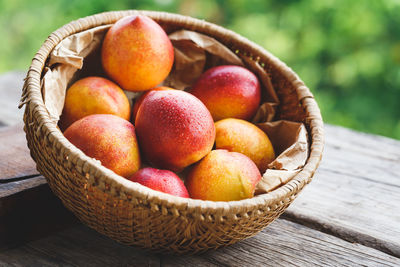 High angle close-up of wet peaches in basket on wooden table
