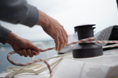 Cropped hands of man with rope on boat