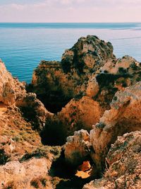 Scenic view of rocks by sea against sky