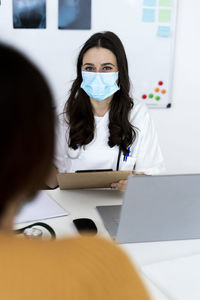 Female doctor talking with patient at clinic during pandemic