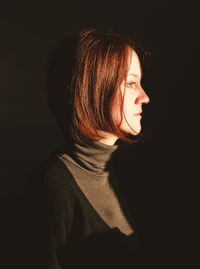 Close-up of young woman over black background