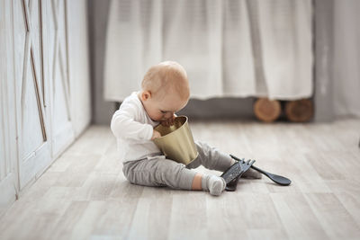  blond kid plays with the kitchen tools on the floor, the concept of childhood and safety.