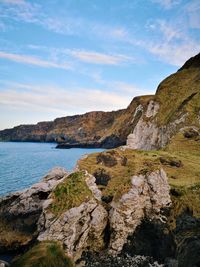 Scenic view of rocks by sea against sky